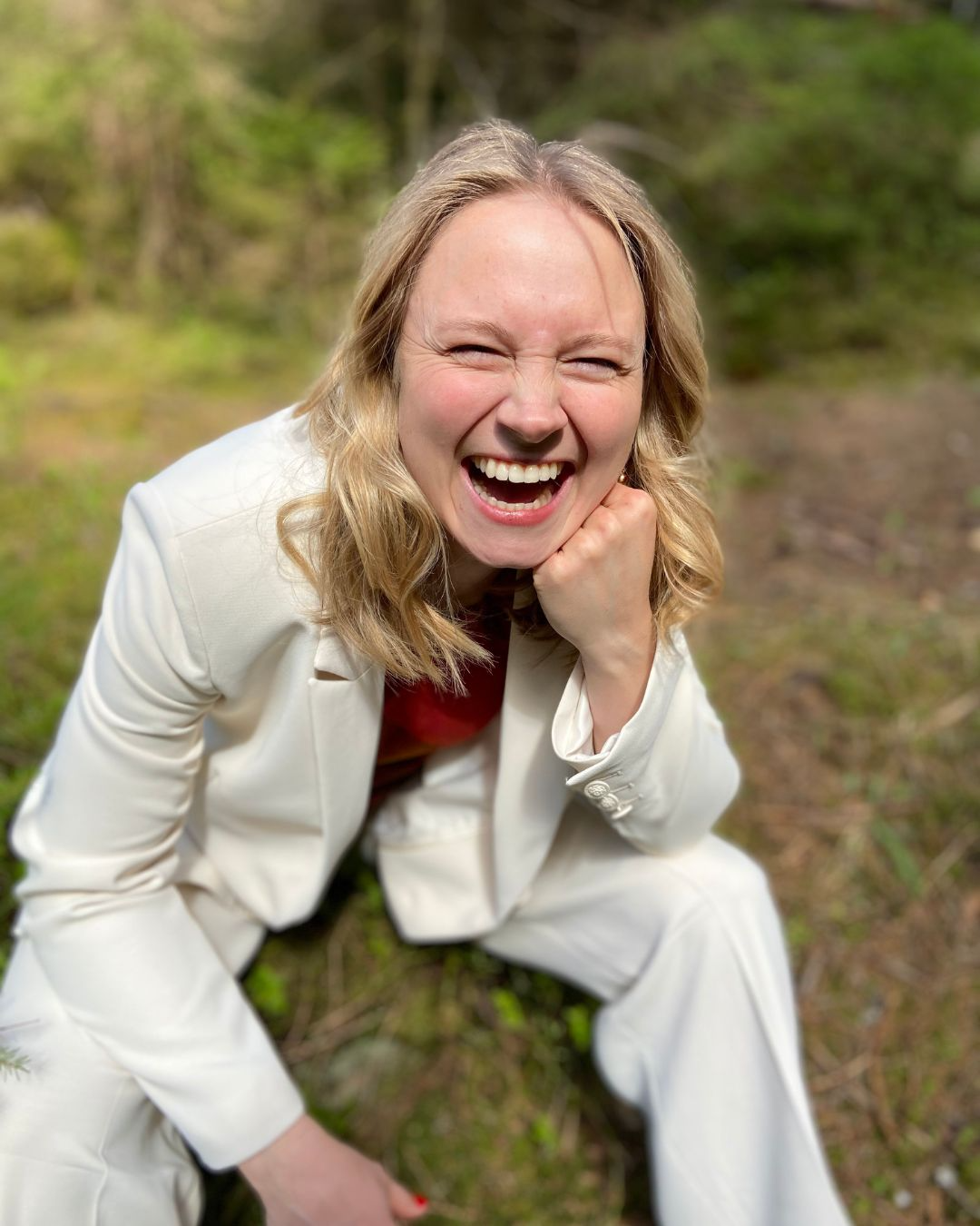 Portrait of Anna Ma laughing in a white suit in the forest